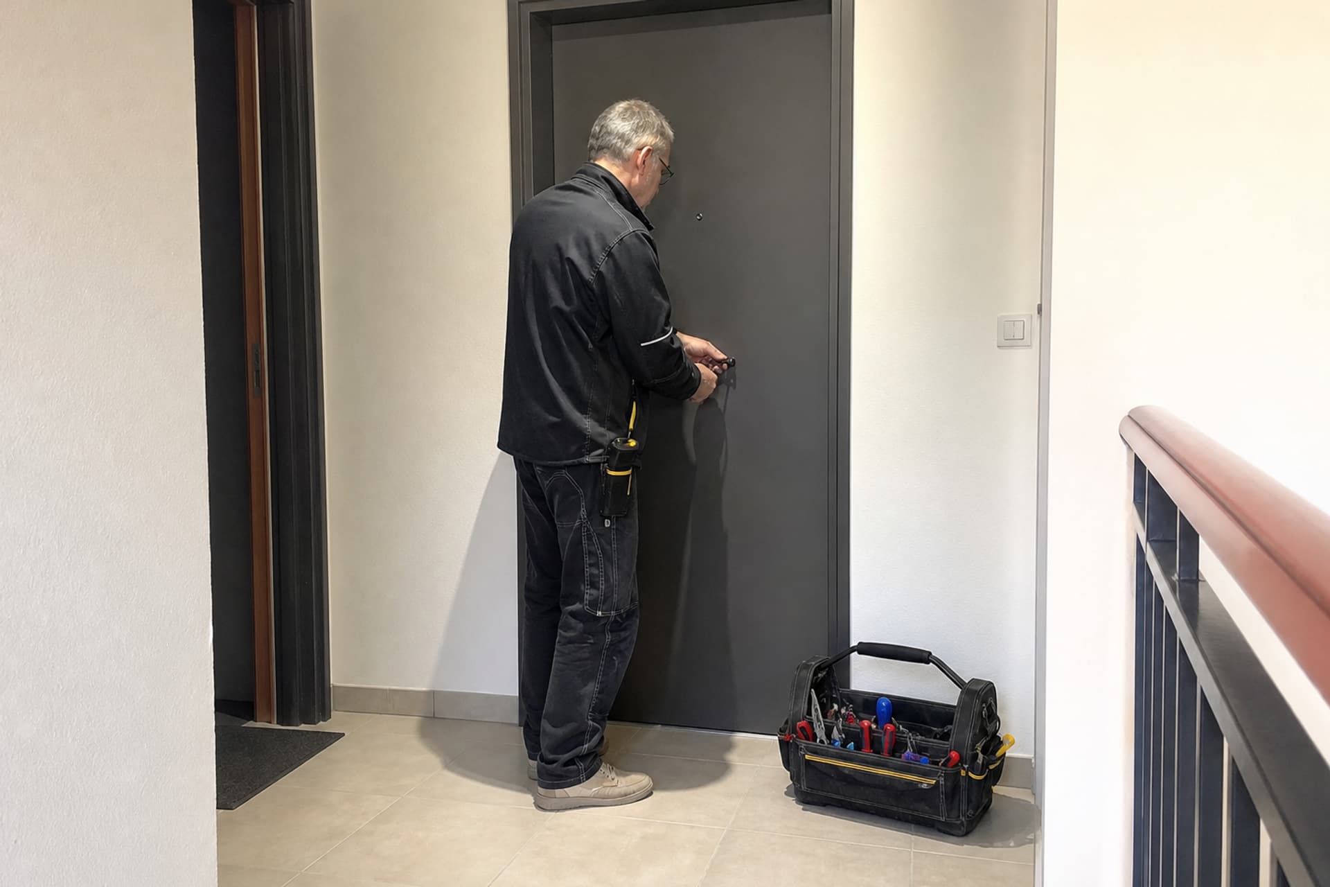 serrurier de profil devant porte, outils au sol